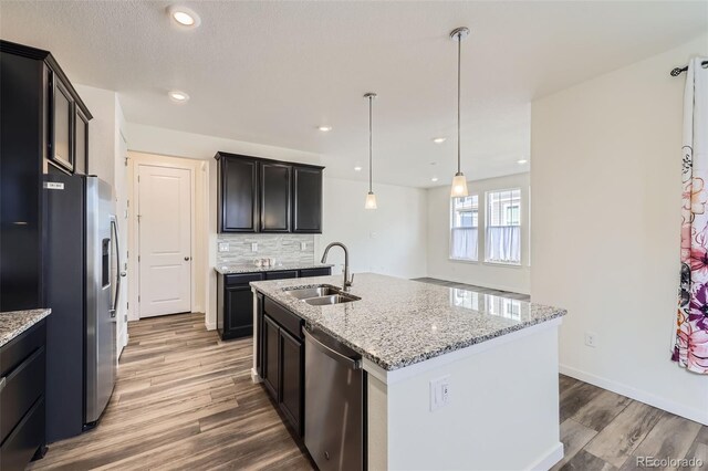 17530 E 95th Ave, Commerce City, CO 80022 - kitchen with stainless steel appliances, a sink, light stone counters, wood finished floors, and recessed lighting