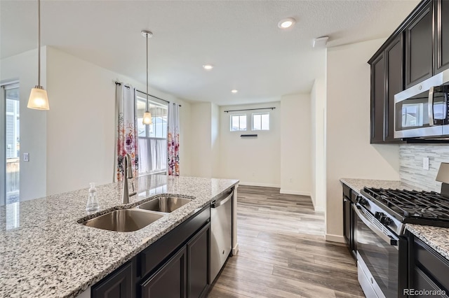 17530 E 95th Ave, Commerce City, CO 80022 - kitchen with stainless steel appliances, a sink, wood finished floors, backsplash, and light stone counters