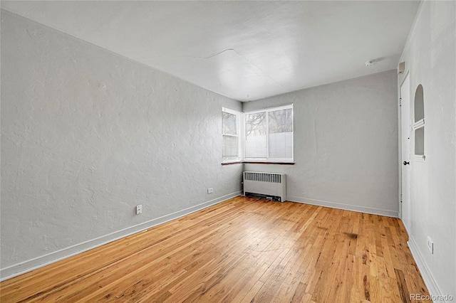 spare room with radiator heating unit and light hardwood / wood-style flooring