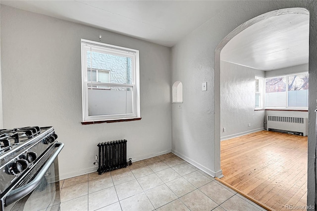 interior space with plenty of natural light, light tile patterned flooring, and radiator heating unit