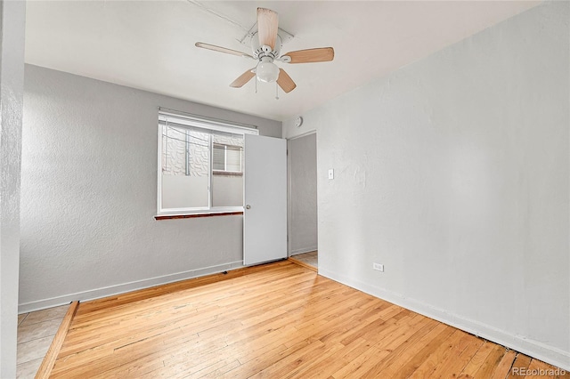 empty room with ceiling fan and light hardwood / wood-style floors