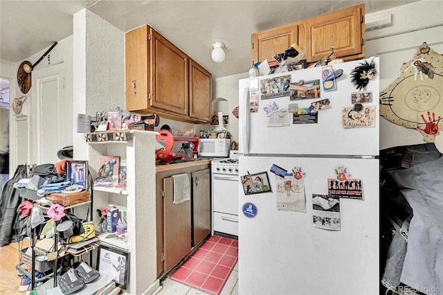 kitchen featuring light tile patterned flooring and white appliances