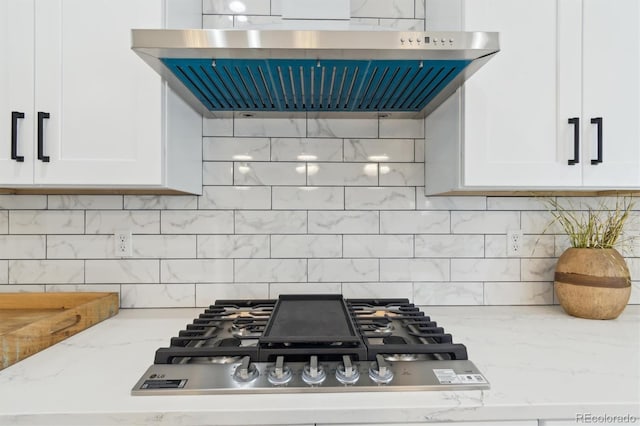 kitchen with light stone counters, stainless steel gas cooktop, white cabinets, decorative backsplash, and exhaust hood