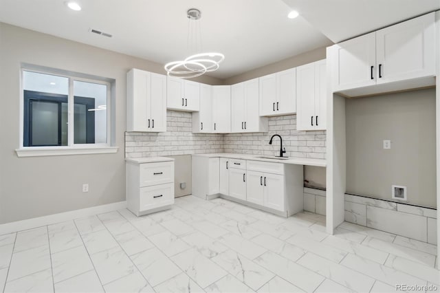 kitchen featuring white cabinetry, decorative light fixtures, sink, and backsplash