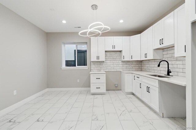 kitchen featuring sink, an inviting chandelier, hanging light fixtures, white cabinets, and decorative backsplash