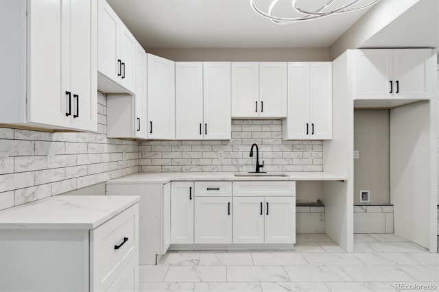 kitchen featuring white cabinetry, light stone countertops, sink, and decorative backsplash