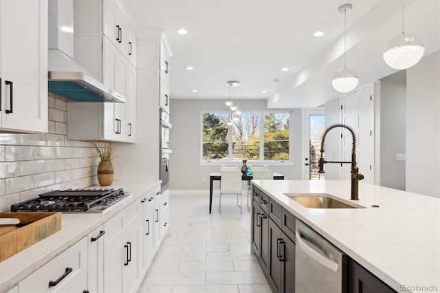 kitchen featuring pendant lighting, white cabinets, appliances with stainless steel finishes, and wall chimney range hood