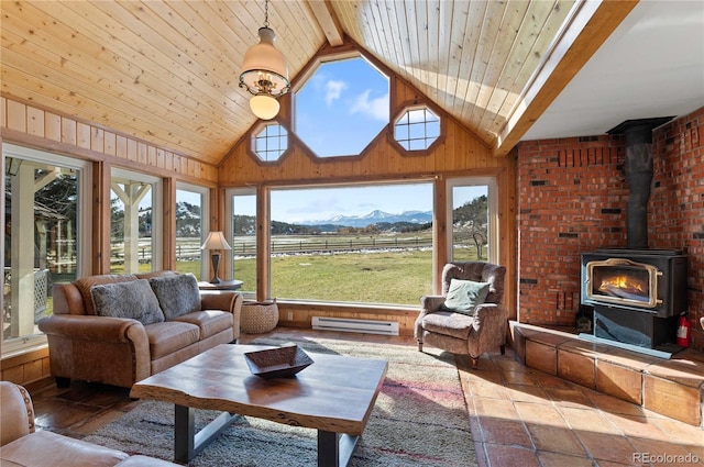 sunroom / solarium with a mountain view, a wood stove, lofted ceiling with beams, a baseboard radiator, and a rural view