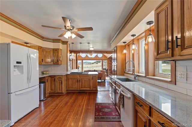 kitchen featuring stainless steel dishwasher, dark wood-type flooring, sink, white refrigerator with ice dispenser, and hanging light fixtures