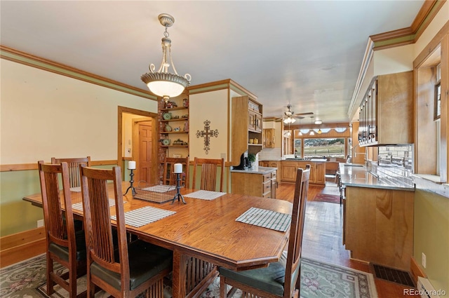 dining space with crown molding, dark hardwood / wood-style flooring, and ceiling fan