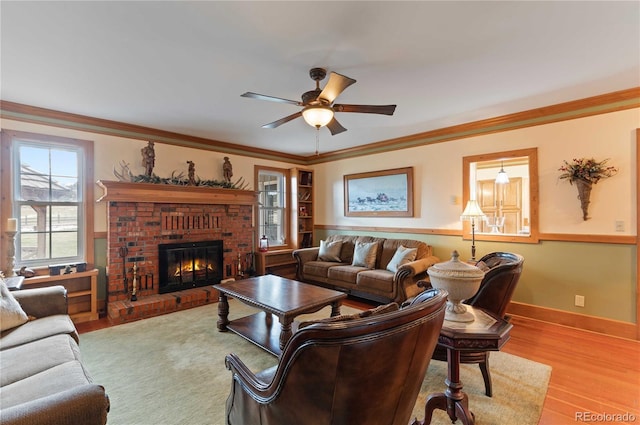 living room featuring a brick fireplace, light hardwood / wood-style flooring, ceiling fan, and crown molding