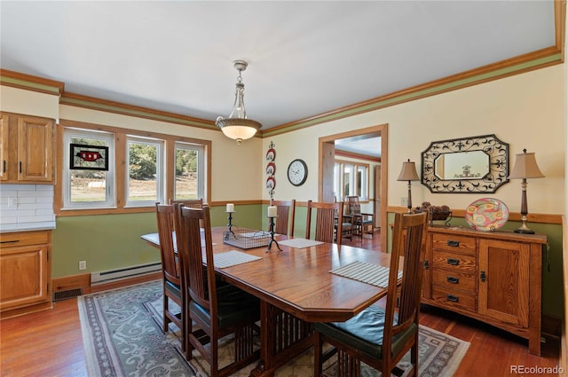 dining area with dark hardwood / wood-style flooring, a baseboard radiator, and crown molding