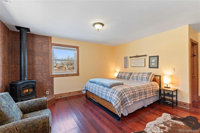 bedroom with a wood stove and dark hardwood / wood-style floors