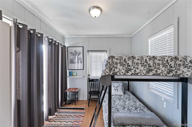 bedroom featuring hardwood / wood-style floors, ornamental molding, and wooden walls