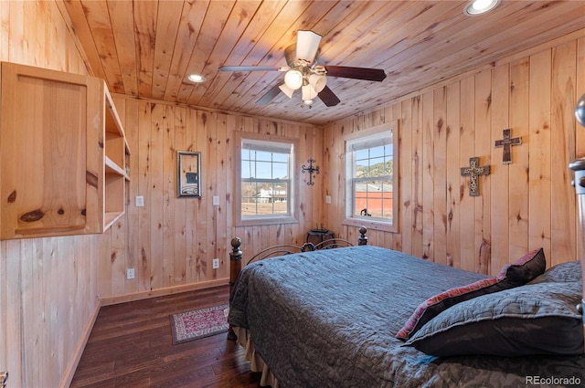 bedroom with ceiling fan, dark hardwood / wood-style flooring, wood ceiling, and wooden walls