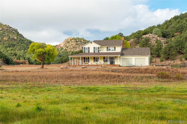 view of front of house featuring a mountain view, covered porch, and a garage