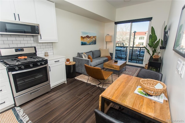 2876 W 53rd Ave Unit 106, Denver, CO 80221 - kitchen featuring appliances with stainless steel finishes, backsplash, white cabinetry, dark wood-style flooring, and light countertops