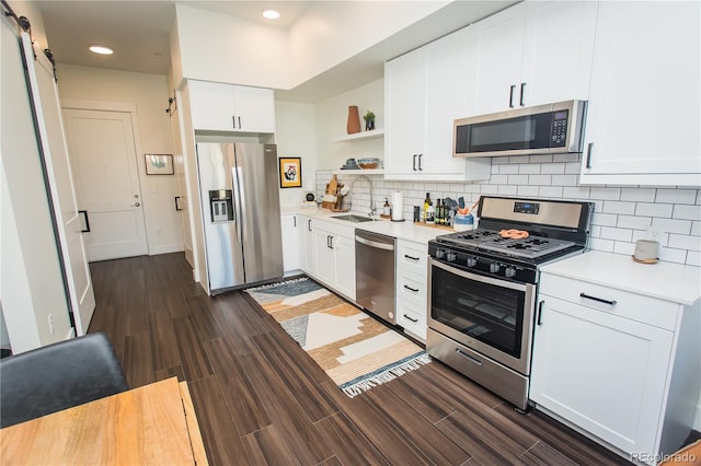 2876 W 53rd Ave Unit 106, Denver, CO 80221 - kitchen featuring stainless steel appliances, open shelves, a sink, a barn door, and light countertops