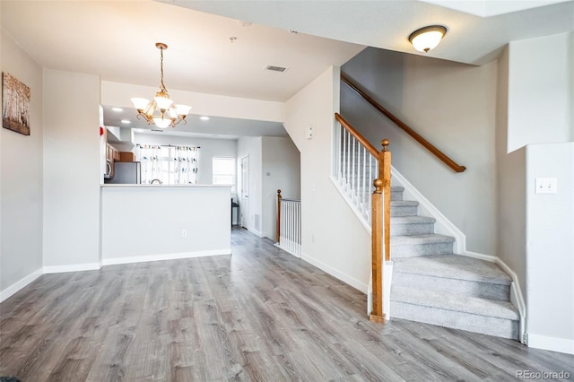 18726 E Yale Cir Unit D, Aurora, CO 80013 - unfurnished living room featuring wood finished floors, a chandelier, baseboards, stairway, and recessed lighting
