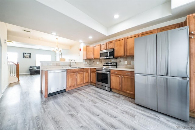 18726 E Yale Cir Unit D, Aurora, CO 80013 - kitchen with appliances with stainless steel finishes, a sink, a peninsula, light countertops, and light wood-style flooring