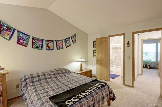 bedroom with vaulted ceiling, light carpet, and connected bathroom