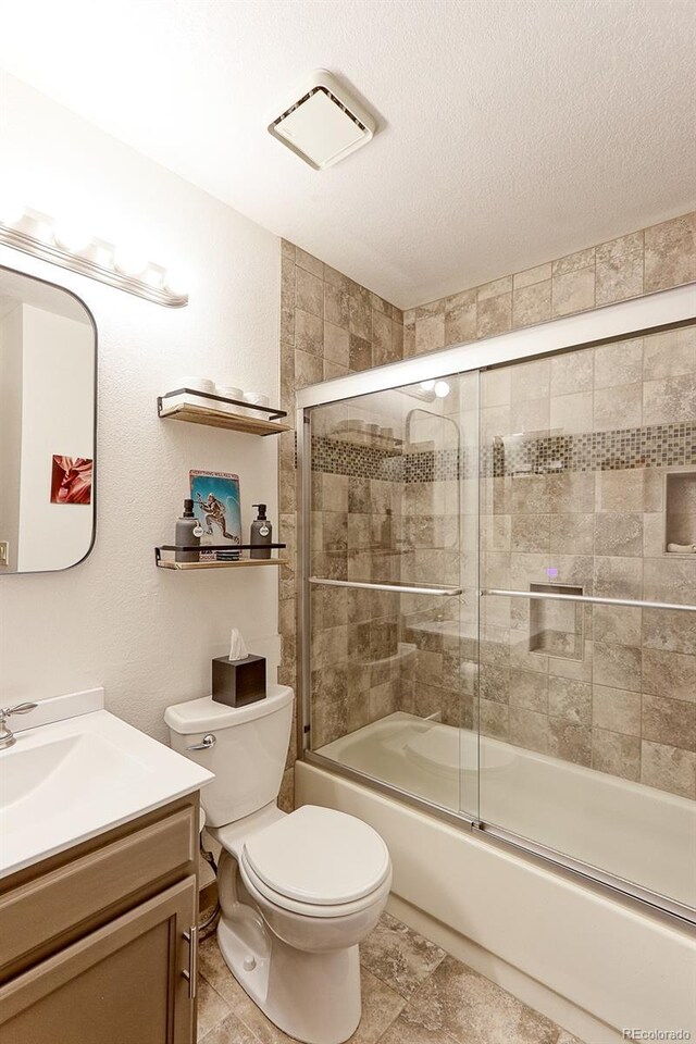 full bathroom with combined bath / shower with glass door, vanity, toilet, and a textured ceiling