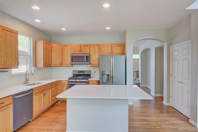 8545 Braun Loop, Arvada, CO 80005 - kitchen featuring stainless steel appliances, a sink, arched walkways, a kitchen island, and light wood finished floors