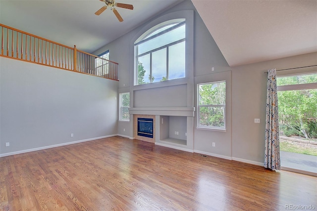 8545 Braun Loop, Arvada, CO 80005 - unfurnished living room featuring high vaulted ceiling, plenty of natural light, a tile fireplace, wood finished floors, and ceiling fan