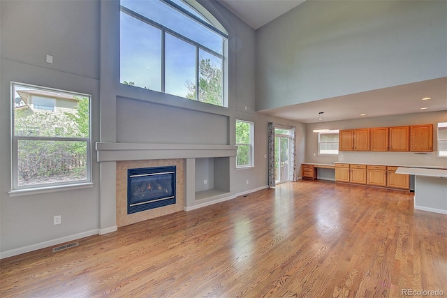 8545 Braun Loop, Arvada, CO 80005 - unfurnished living room with a high ceiling, baseboards, light wood-style floors, and healthy amount of natural light