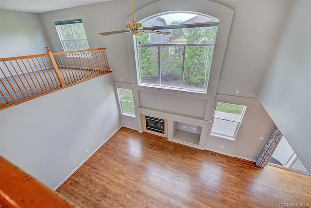 8545 Braun Loop, Arvada, CO 80005 - unfurnished living room with wood finished floors, a glass covered fireplace, ceiling fan, baseboards, and a high ceiling