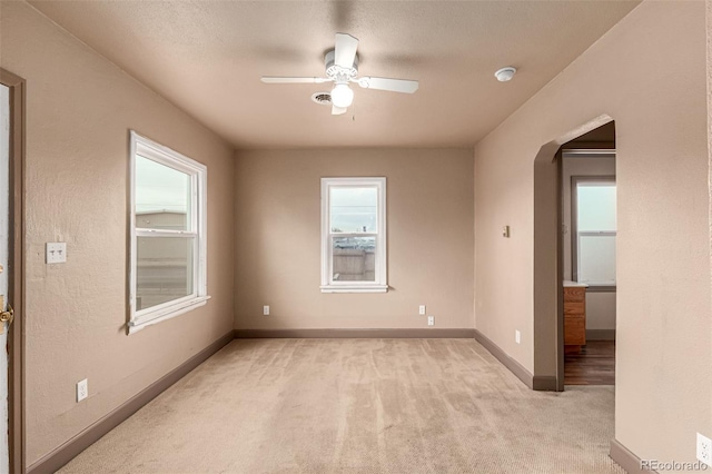 spare room featuring ceiling fan, light carpet, and a textured ceiling