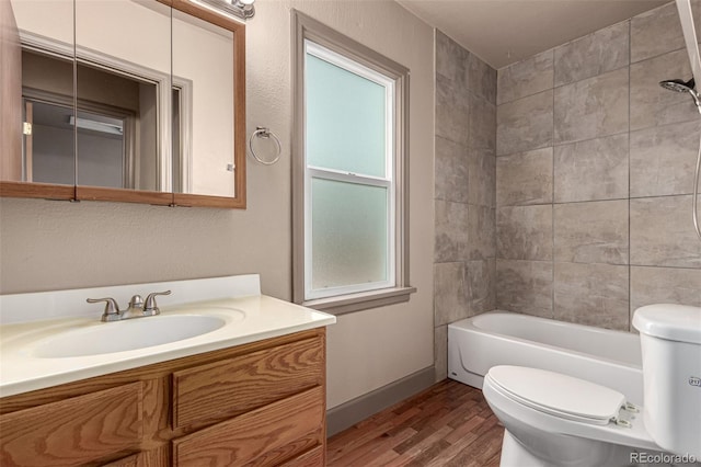 full bathroom featuring vanity, hardwood / wood-style floors, tiled shower / bath, and toilet