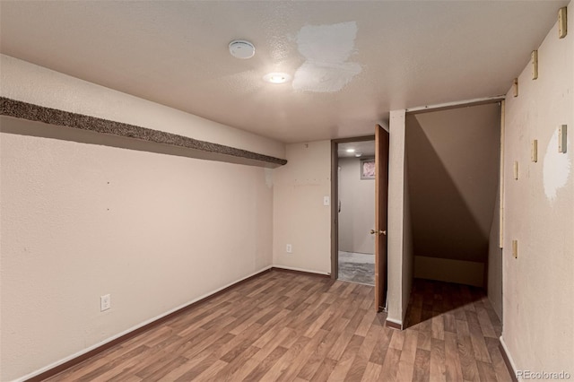 basement featuring hardwood / wood-style flooring and a textured ceiling