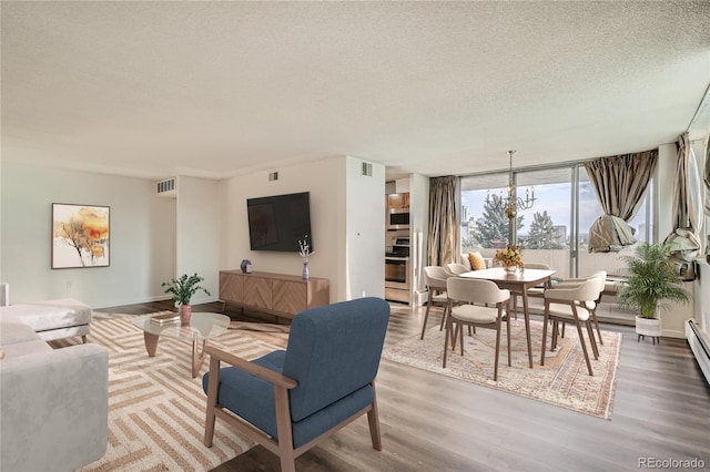 living room featuring wood-type flooring, a textured ceiling, a wall of windows, and a chandelier