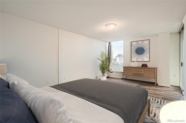 bedroom with hardwood / wood-style flooring, a baseboard radiator, and a textured ceiling