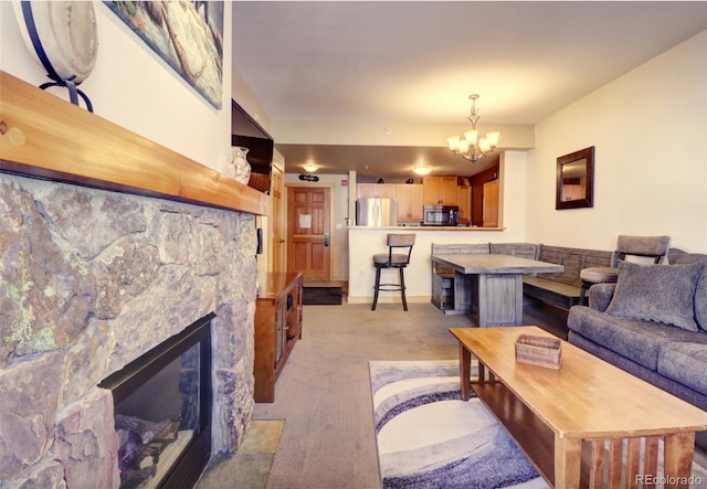 living area with a chandelier, light carpet, and a stone fireplace