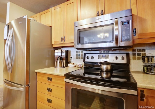 kitchen featuring light brown cabinetry, stainless steel appliances, decorative backsplash, and light countertops