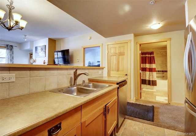 kitchen with a sink, light countertops, appliances with stainless steel finishes, decorative backsplash, and pendant lighting