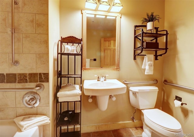 full bathroom with toilet, a sink, tile patterned floors, baseboards, and a tub