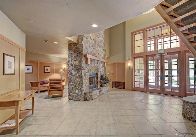 living area featuring french doors, a fireplace, tile patterned flooring, and a high ceiling