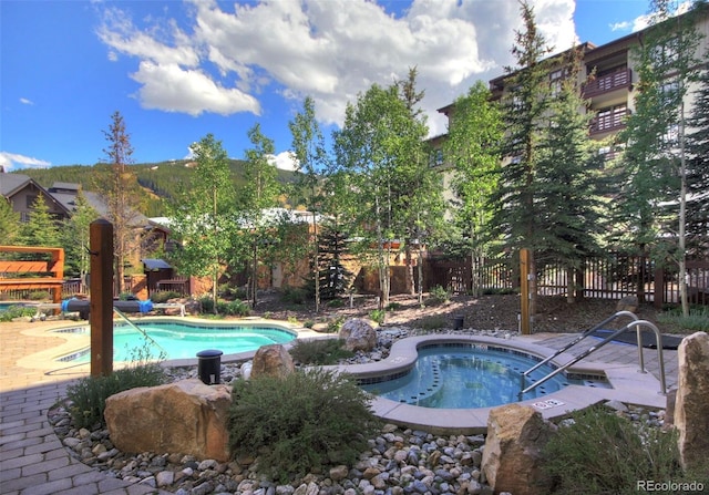 community pool with a community hot tub and fence