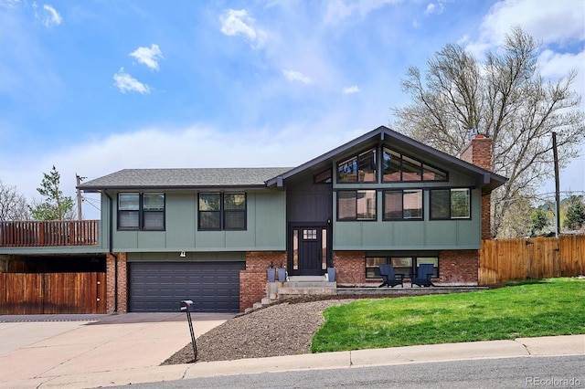 raised ranch with driveway, a chimney, a garage, brick siding, and fence