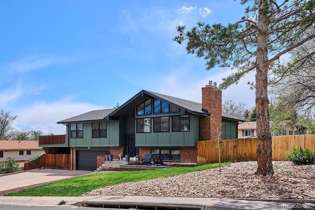 split foyer home featuring fence, a chimney, board and batten siding, an attached garage, and driveway