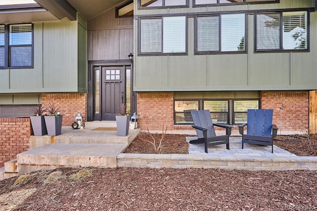 view of exterior entry with brick siding and a patio area