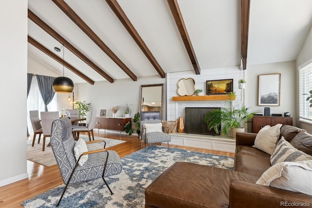 living room with baseboards, a large fireplace, vaulted ceiling with beams, and wood finished floors