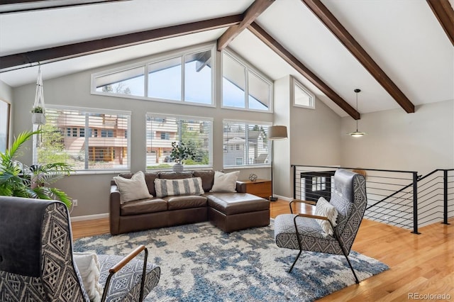 living area featuring baseboards, lofted ceiling with beams, a healthy amount of sunlight, and wood finished floors