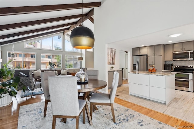 dining room featuring light wood-type flooring, high vaulted ceiling, and beamed ceiling