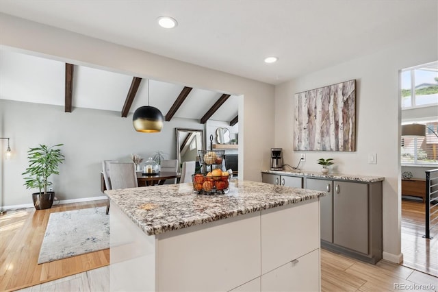 kitchen featuring gray cabinets, light stone countertops, baseboards, vaulted ceiling with beams, and light wood-style flooring