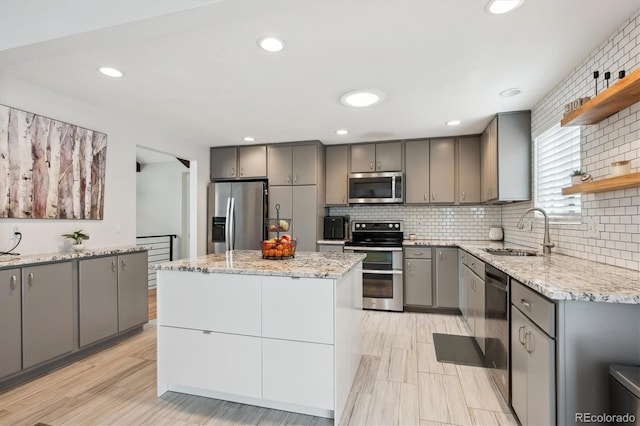 kitchen with open shelves, appliances with stainless steel finishes, a sink, gray cabinets, and tasteful backsplash