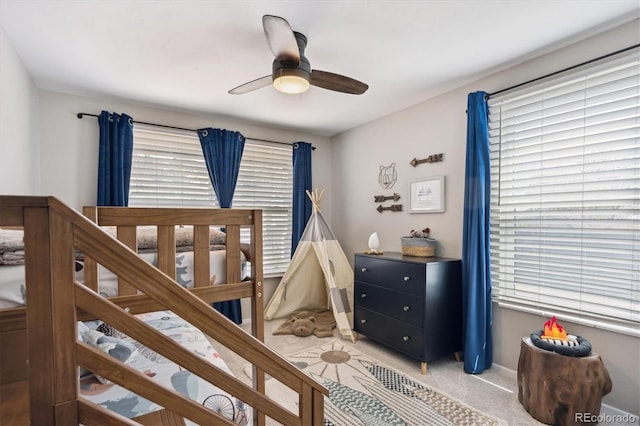 bedroom with a ceiling fan, baseboards, and light carpet